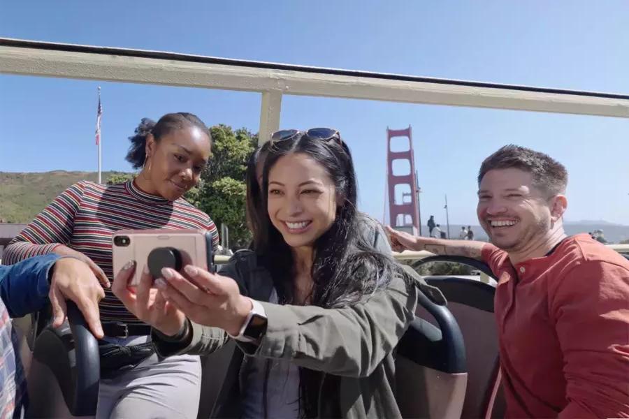 Un grupo de visitantes se toma una selfie en un recorrido en autobús cerca del puente Golden Gate. 加州贝博体彩app.