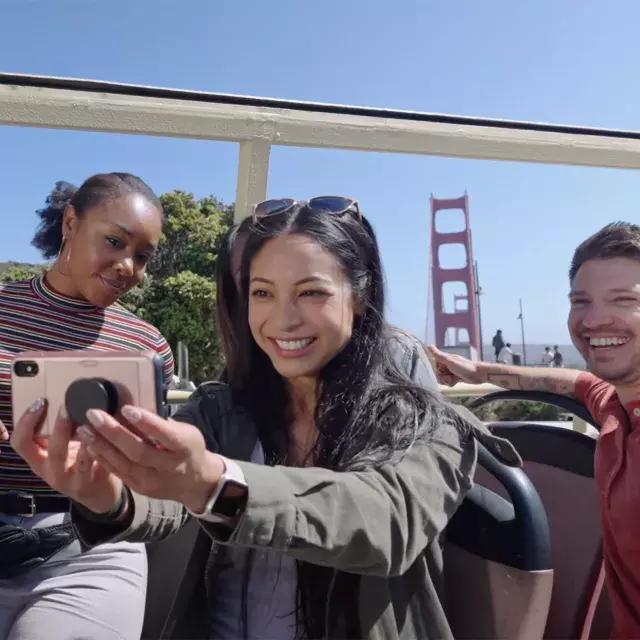 Un grupo de visitantes se toma una selfie en un recorrido en autobús cerca del puente Golden Gate. 加州贝博体彩app.